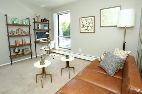 a living room with a brown leather couch and two tables