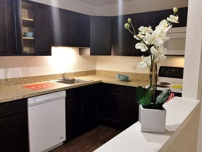 a small kitchen with a vase of flowers on the counter