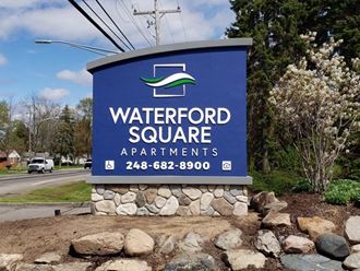 a sign for waterford square apartments on the side of a road