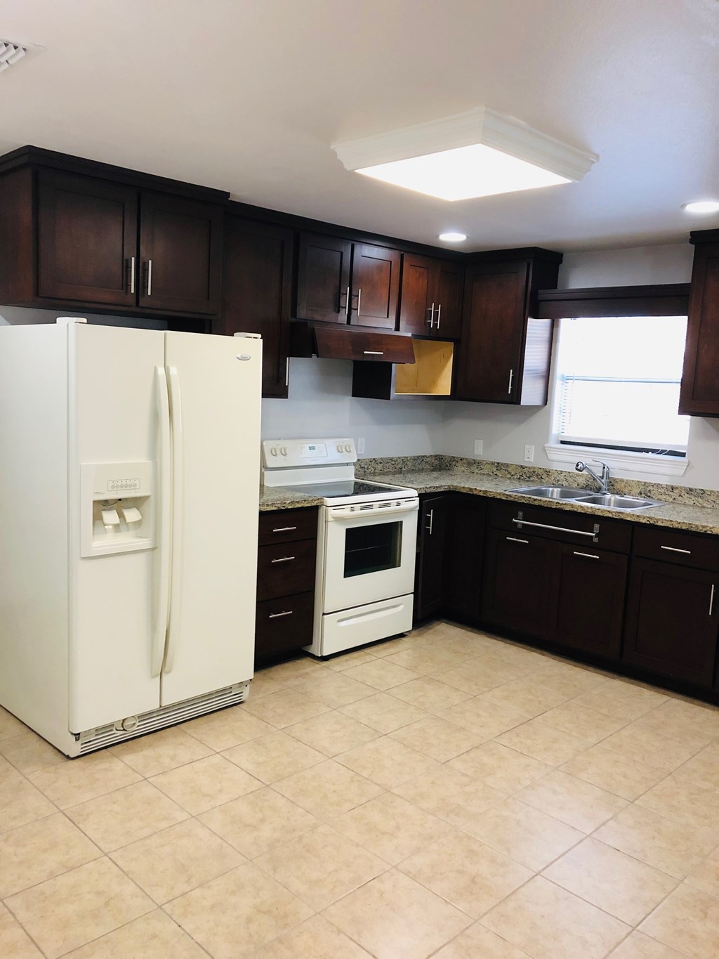 an empty kitchen with a refrigerator and a stove