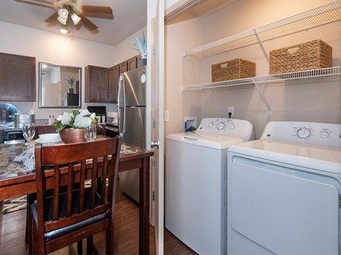 a kitchen with a washer and dryer and a dining table with a chair