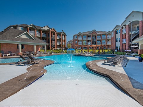 a swimming pool with a fountain in front of an apartment building