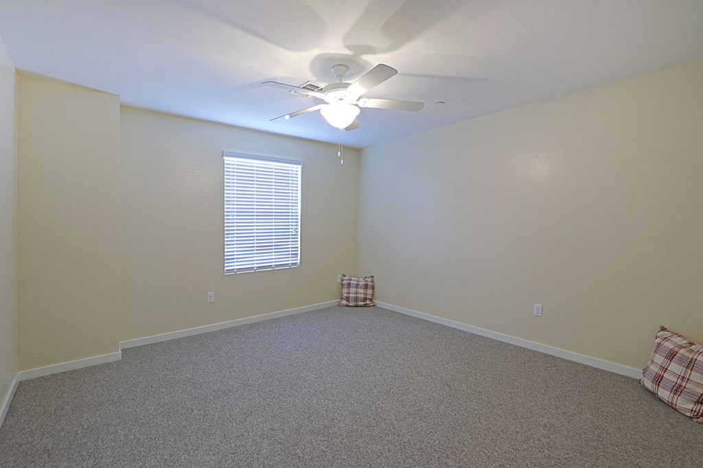 an empty room with a ceiling fan and a window