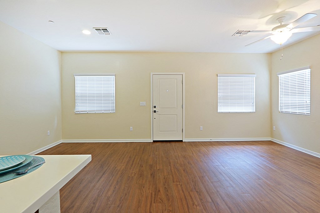 an empty living room with wood floors and a white door