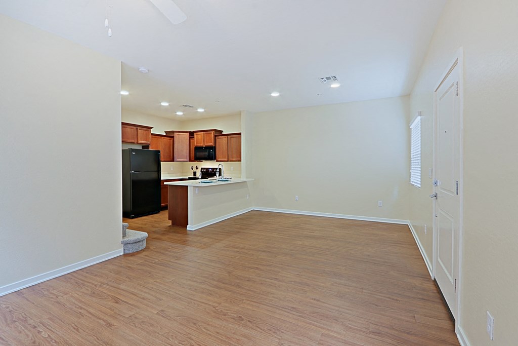 an empty living room and kitchen with a hard wood floor