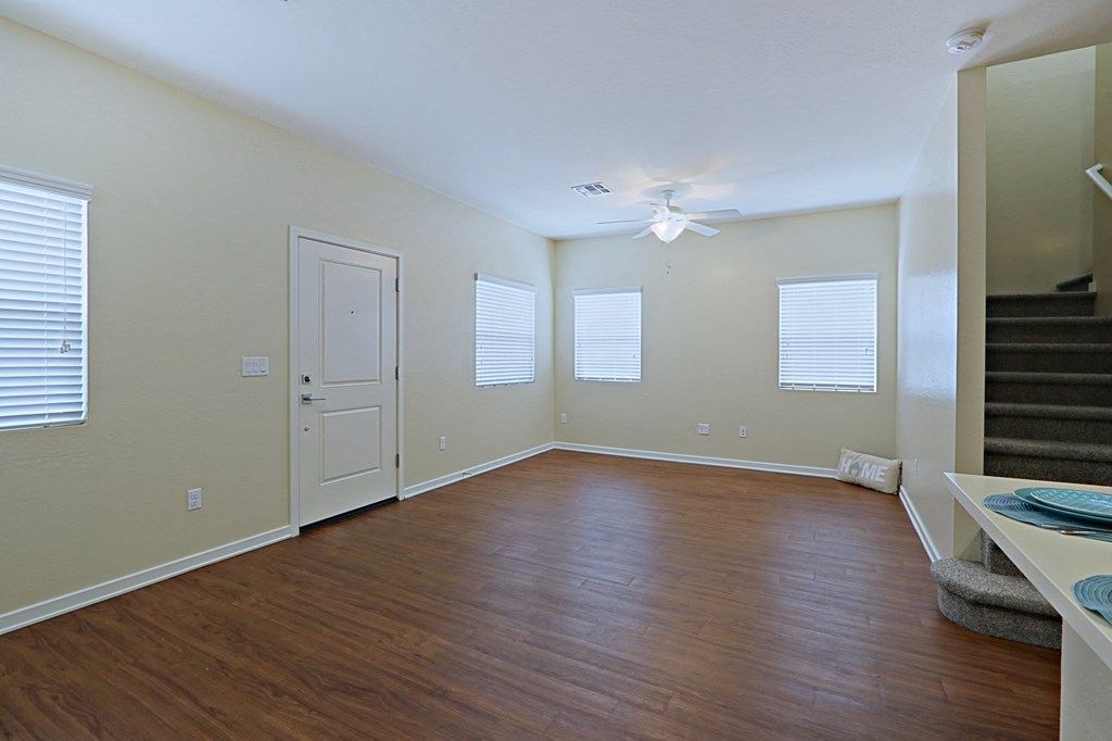 an empty living room with wood floors and a ceiling fan