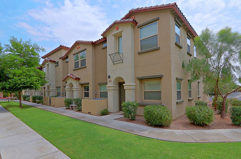 a sidewalk in front of a building with grass and trees