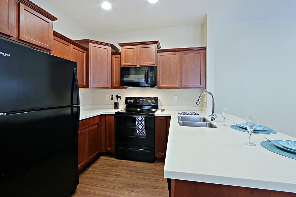 a kitchen with black appliances and wooden cabinets and white counter tops