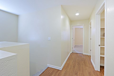a renovated living room and hallway with white walls and wood flooring