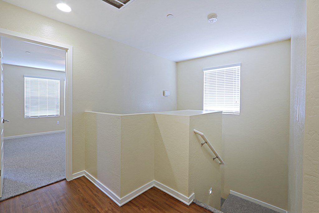an empty room with a white wall and a staircase