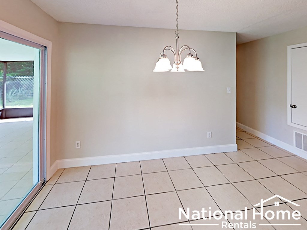 A National Home Rentals sign is displayed in an empty room with tile flooring and a chandelier.