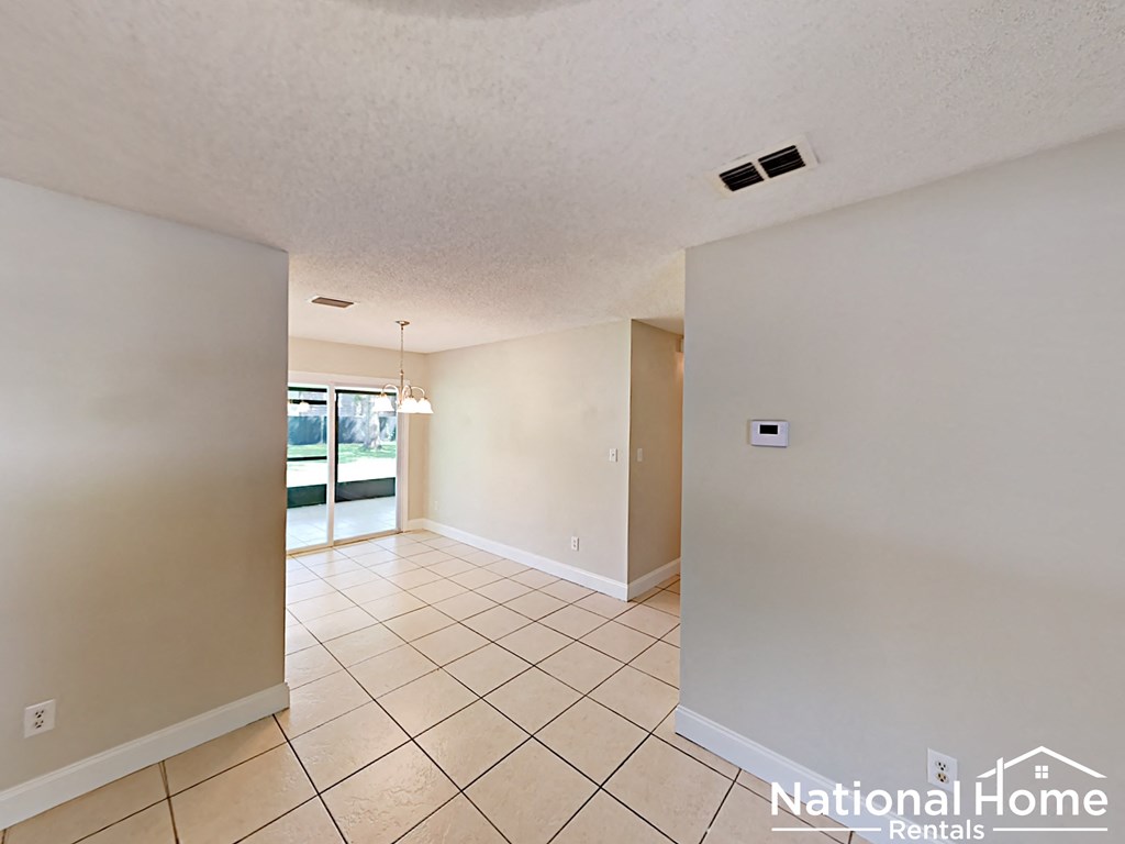 A spacious room with tiled flooring and a doorway leading to another room.