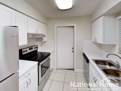 A kitchen with white cabinets and a black stove top oven.