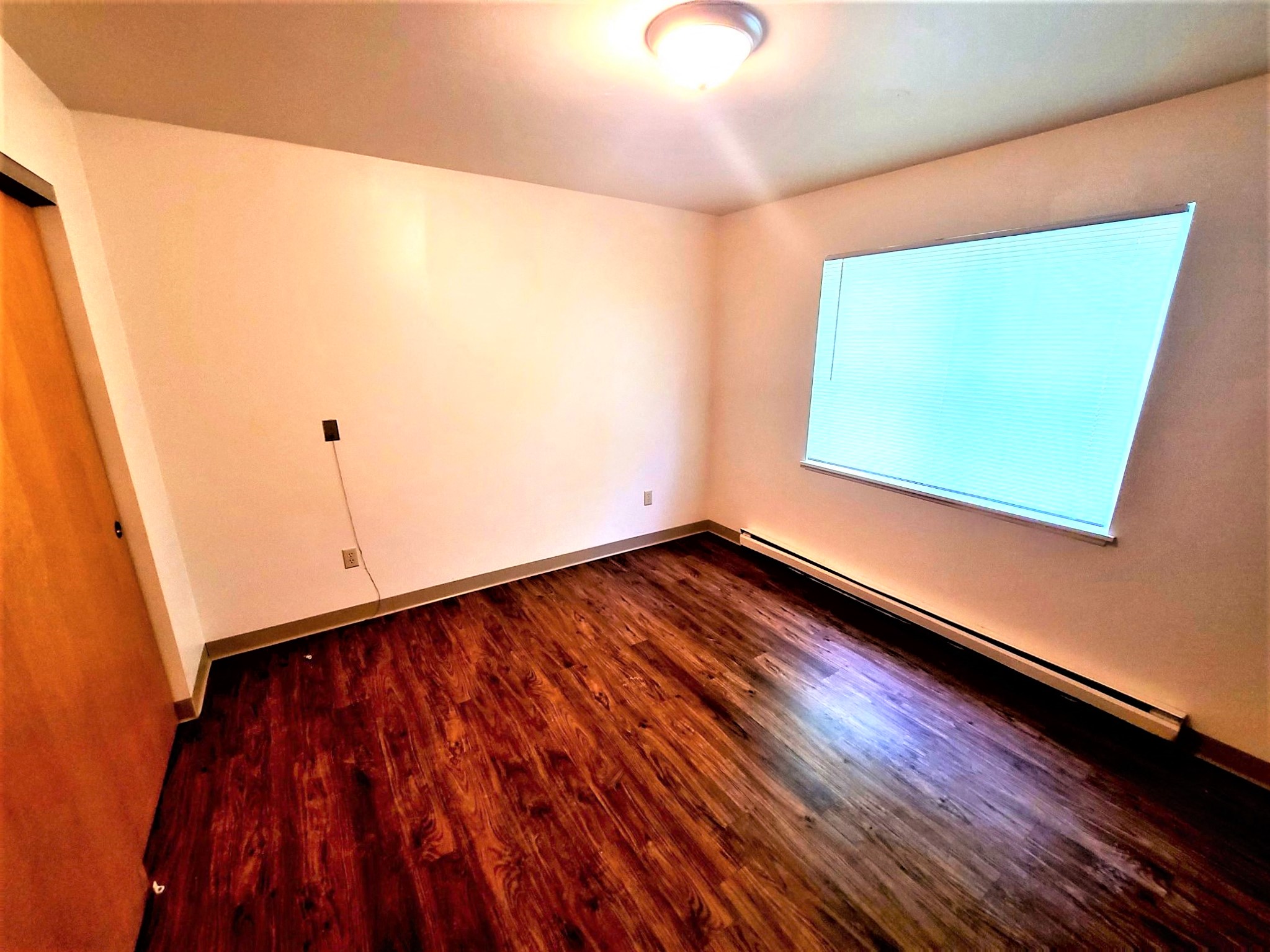a empty room with a window and wooden floors