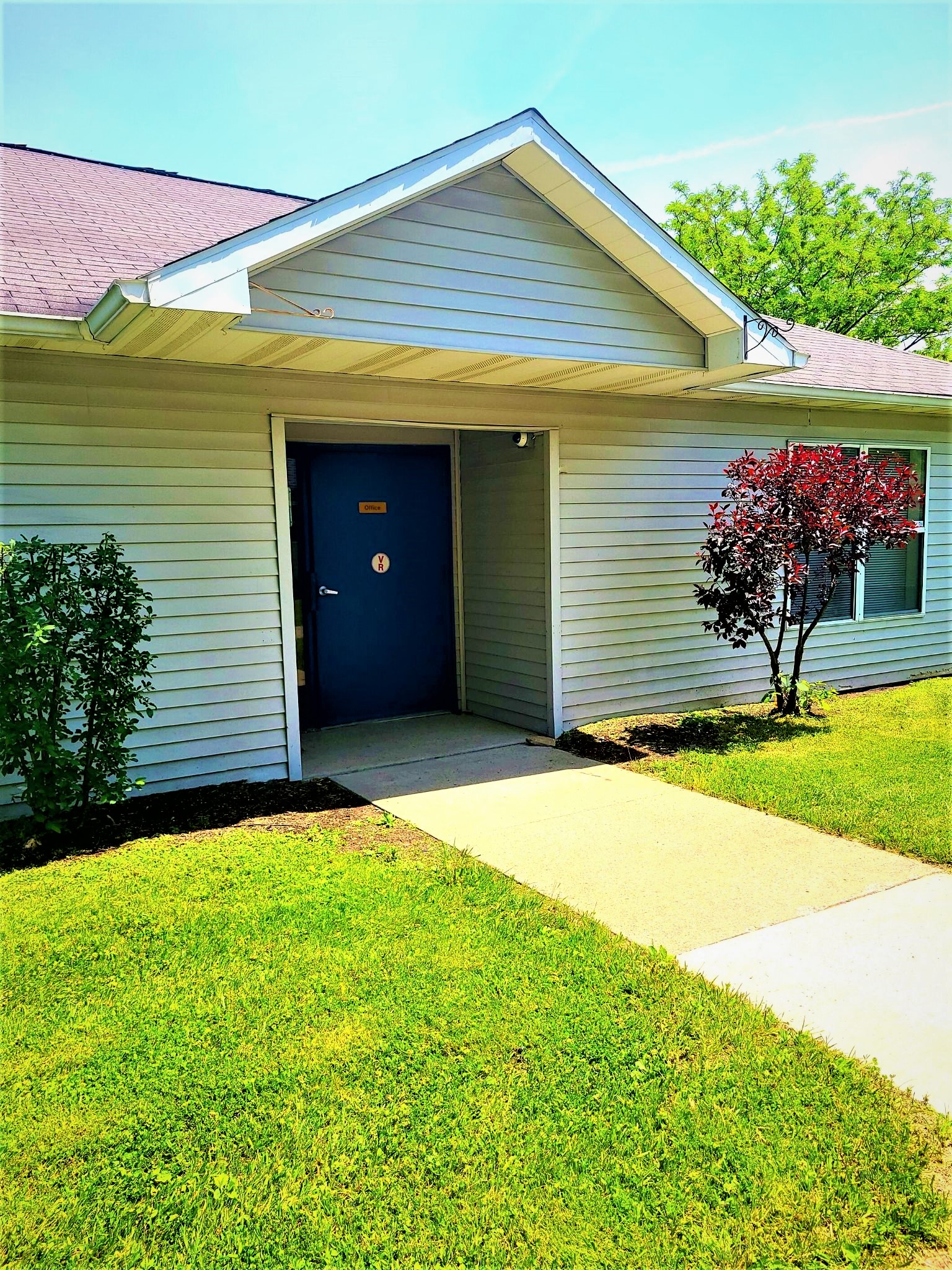 the front of a white house with a blue door