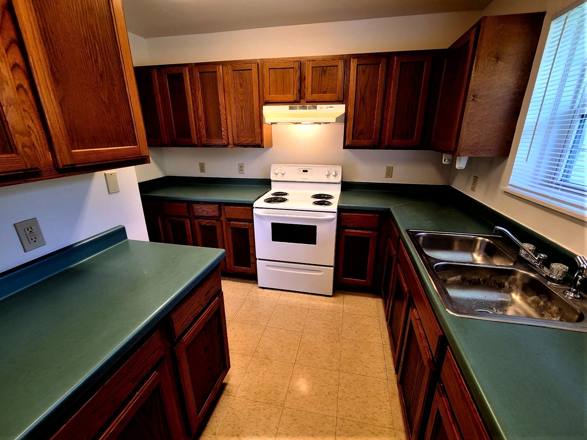 a kitchen with green counters and a stove and a sink