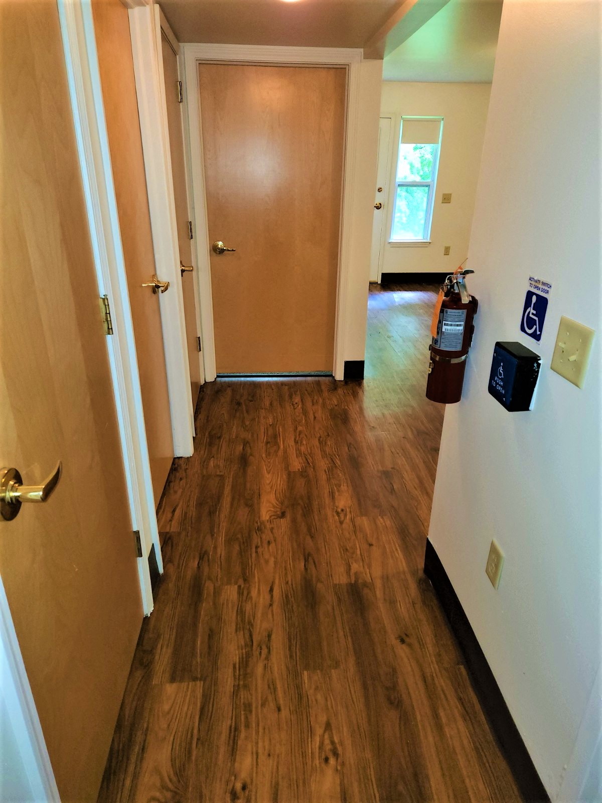 a hallway with wood flooring and a door into a house