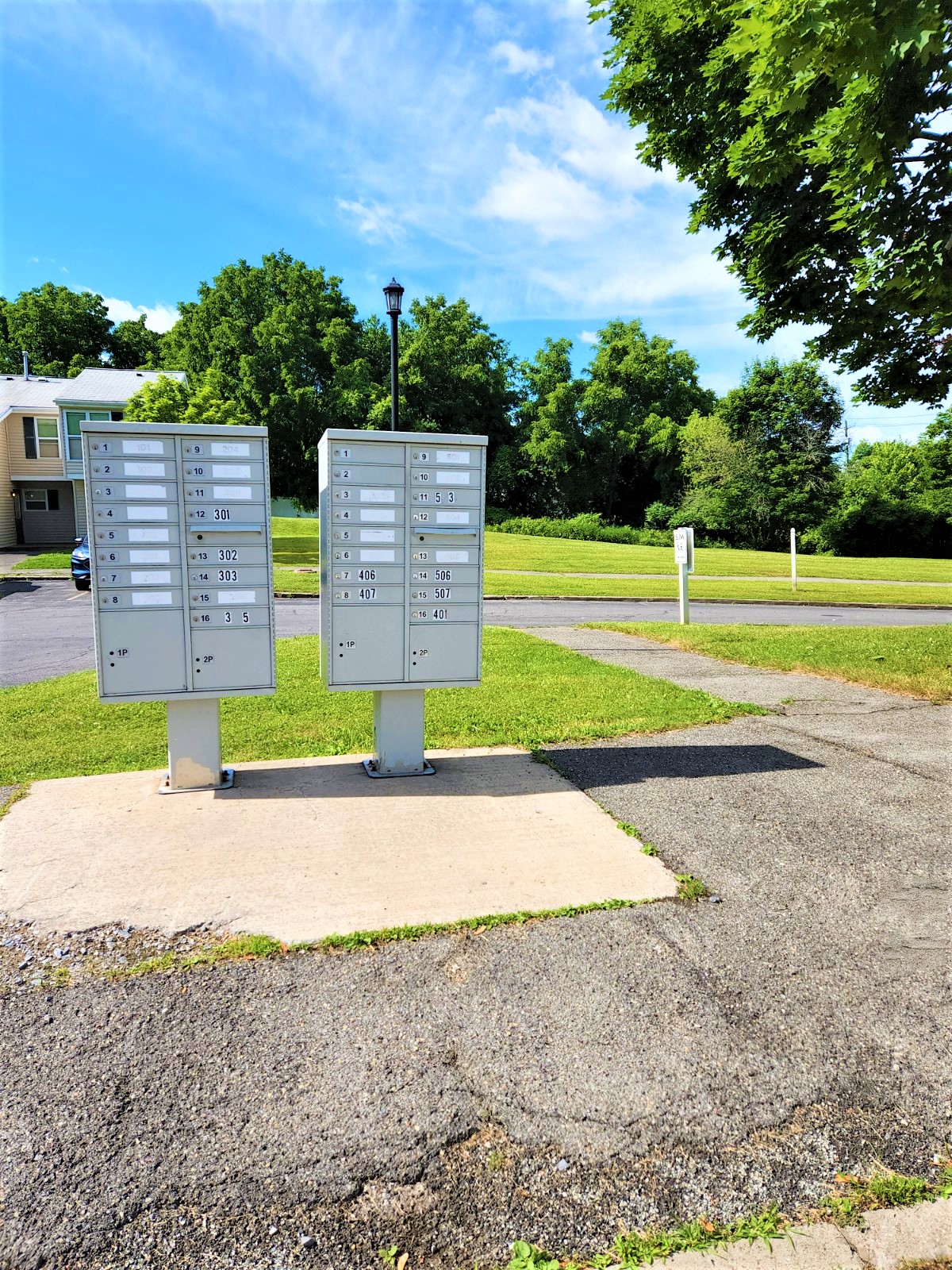 two electrical boxes on a sidewalk next to a field