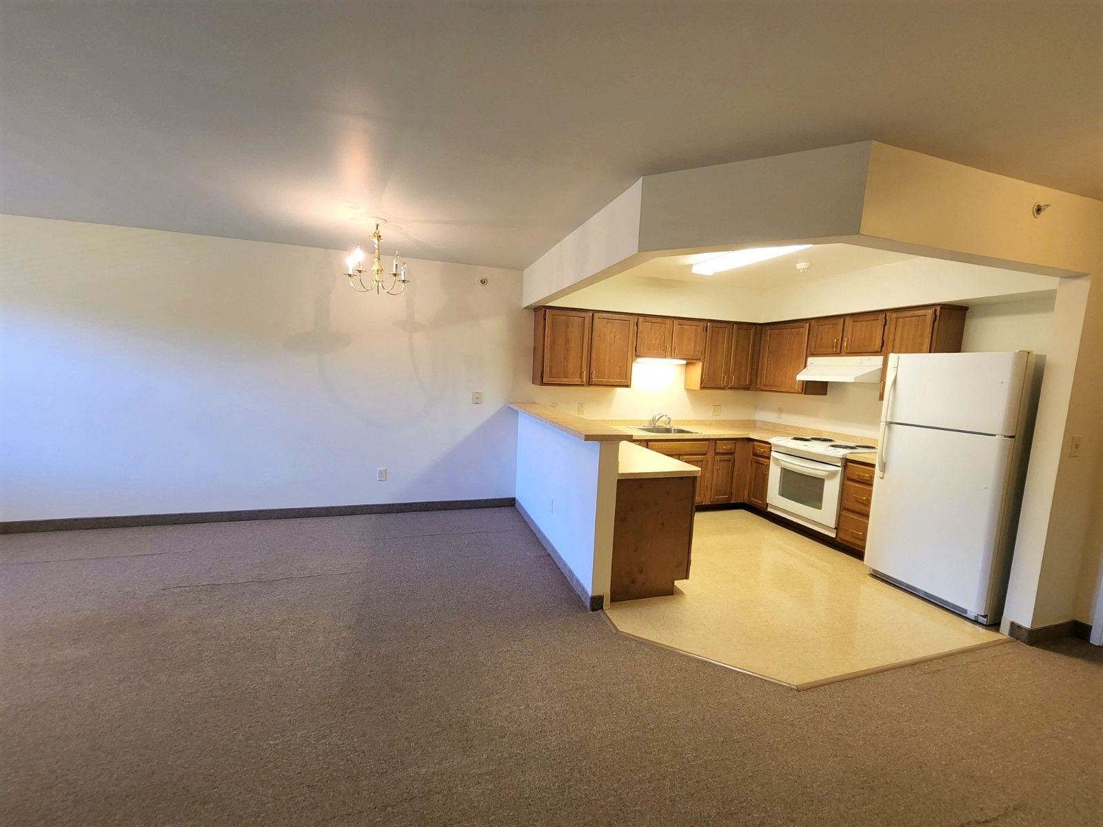 an empty kitchen with white appliances and wooden cabinets