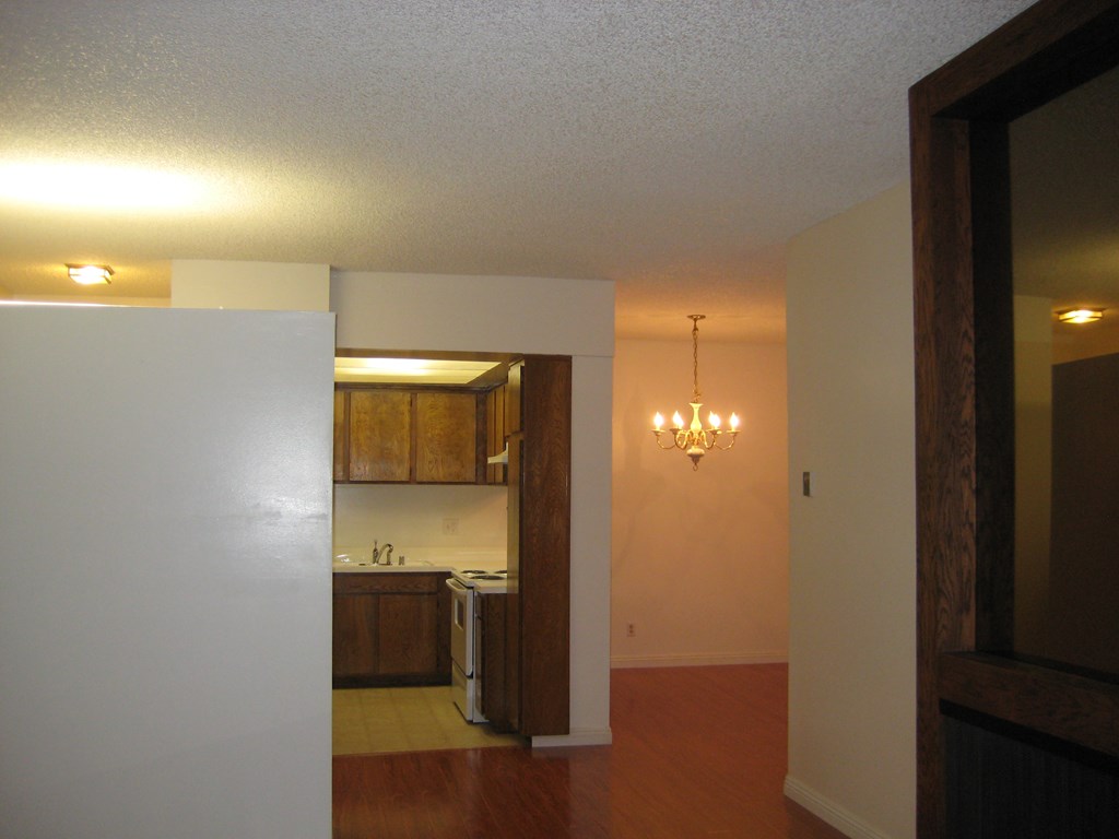 an empty kitchen and living room with a door open