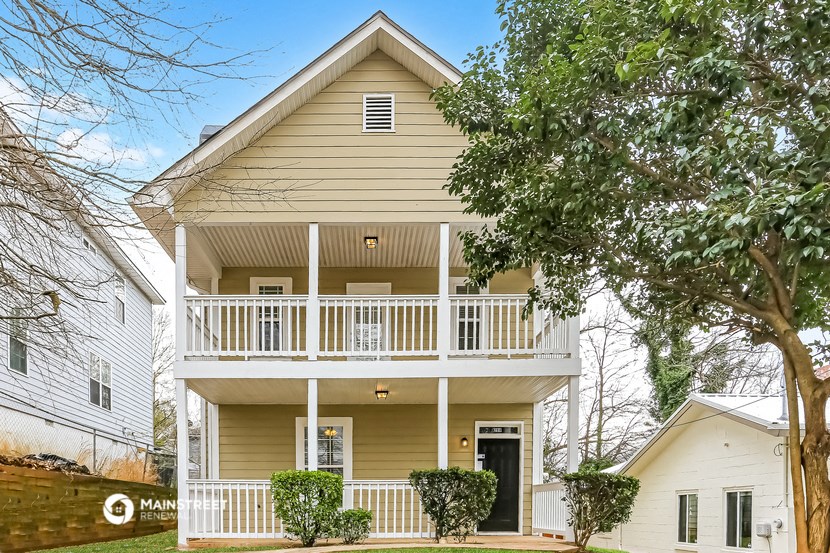 the front of a yellow house with a white balcony