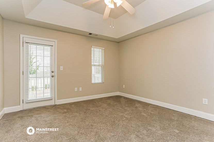 the spacious living room of a home with a ceiling fan