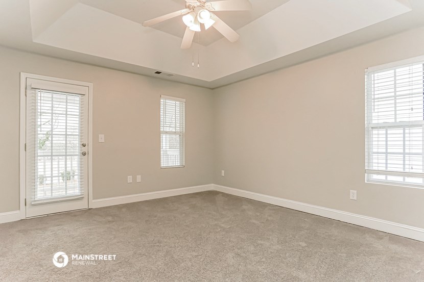 the spacious living room of a home with a ceiling fan