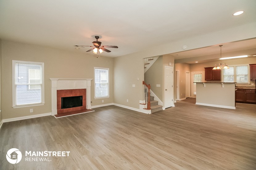 a living room with a fireplace and a ceiling fan