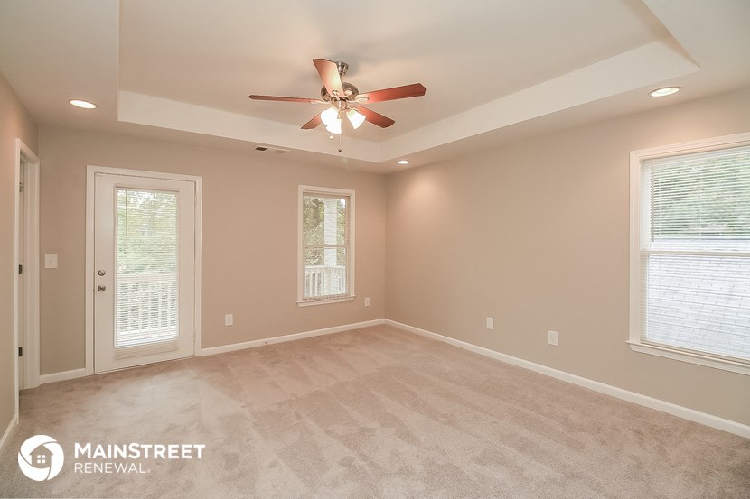 the master bedroom after the remodel with new carpet and a ceiling fan
