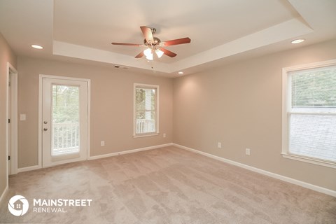 the master bedroom after the remodel with new carpet and a ceiling fan
