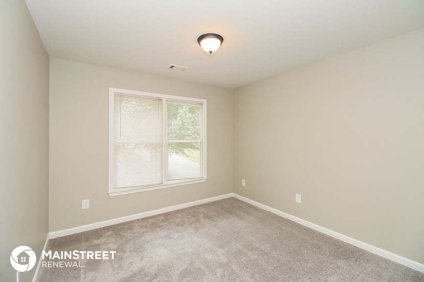 the spacious bedroom with carpeted flooring and a large window