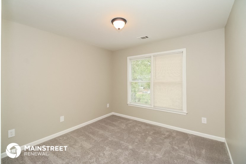 the spacious bedroom with carpeted flooring and a large window