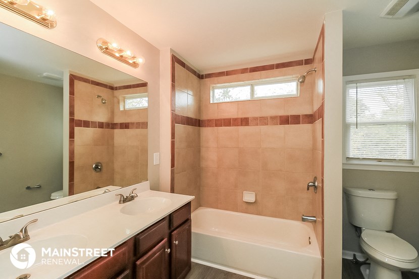 a bathroom with a tub sink and toilet and a mirror