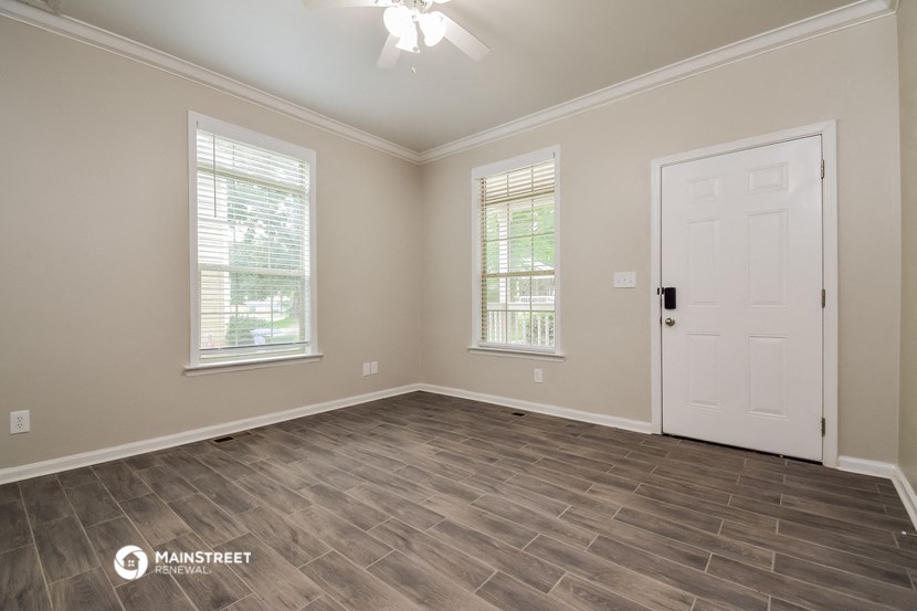 the living room of a home with a white door and wood floors