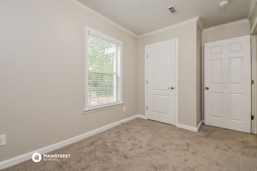 the bedroom of a house with a white door and a window