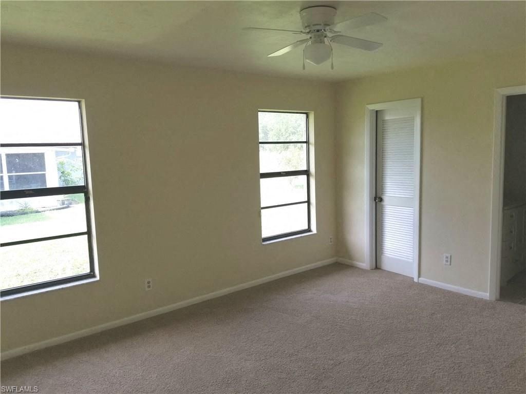 an empty living room with a ceiling fan and two windows