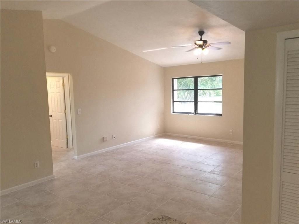 an empty living room with a ceiling fan