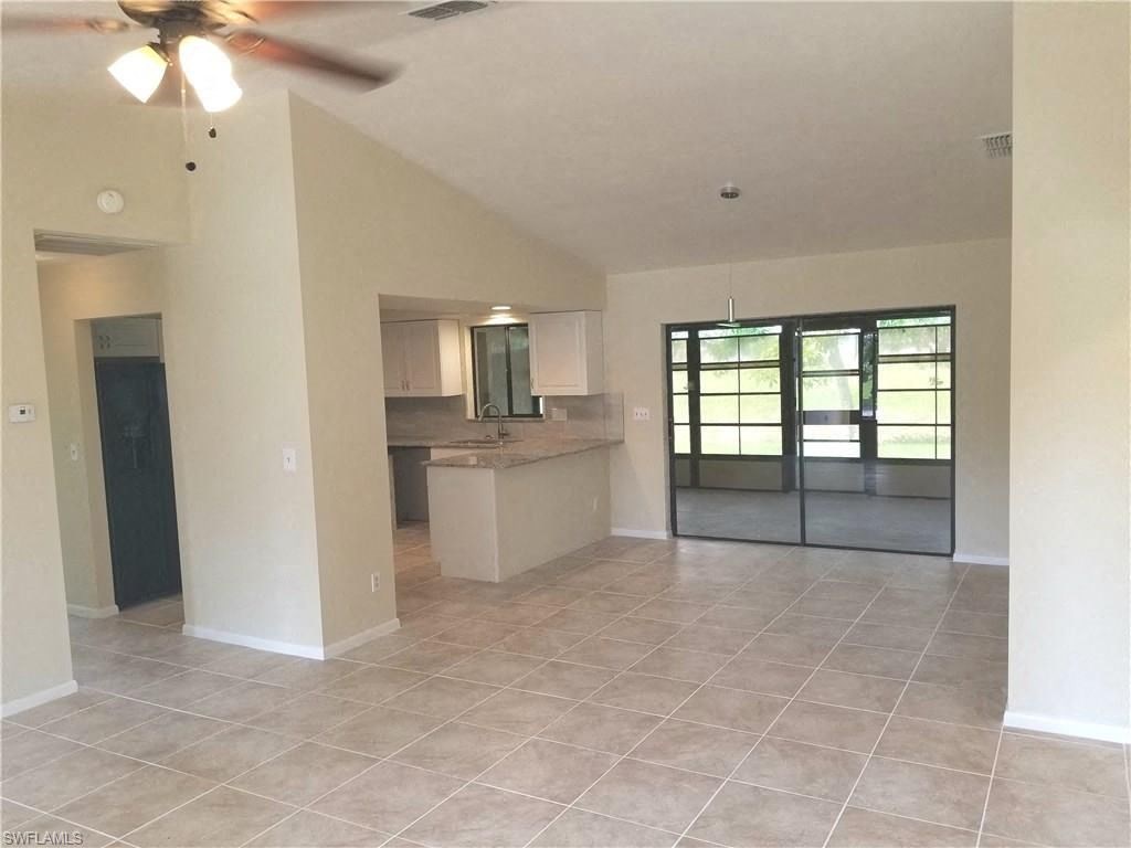 an empty living room and kitchen with a ceiling fan