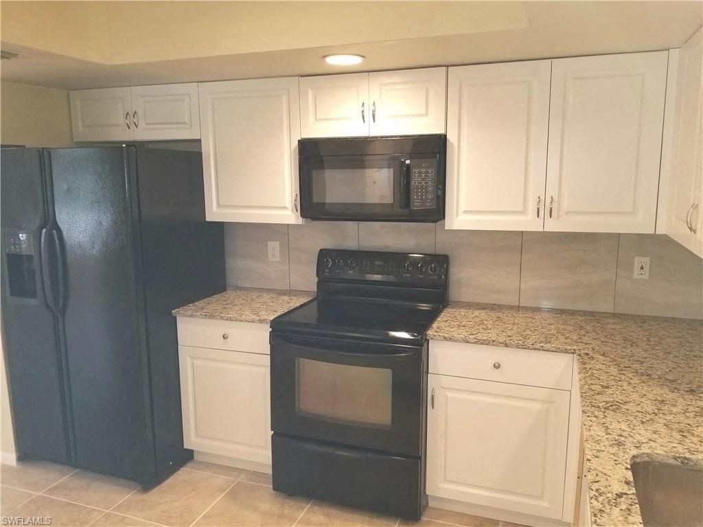 a kitchen with black appliances and white cabinets