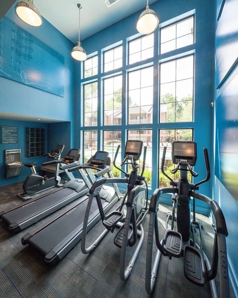 a gym with cardio machines and windows
