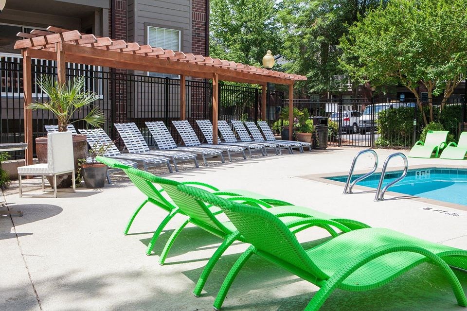 a pool with green chairs next to a swimming pool