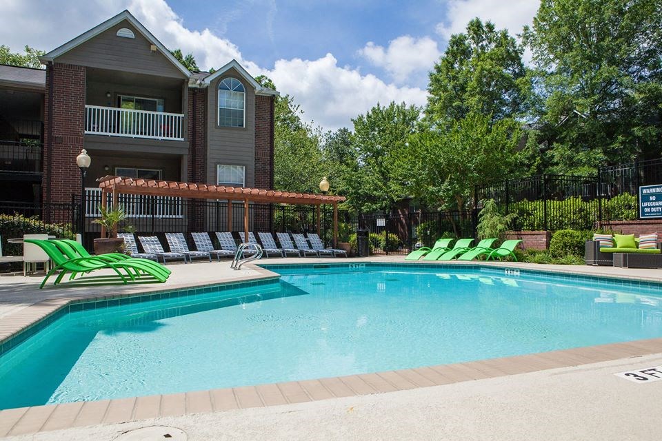 a swimming pool with green chairs around it