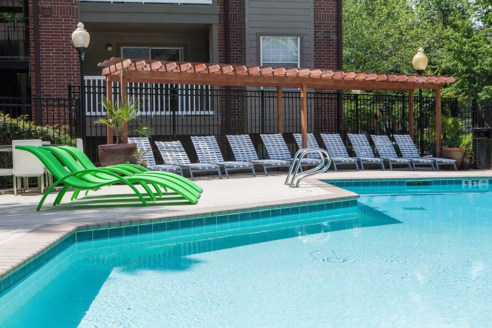a swimming pool with green chairs next to it