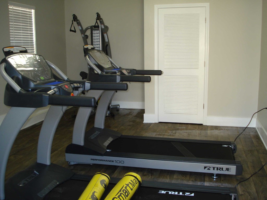 a home gym with two treadmills in the corner of a room