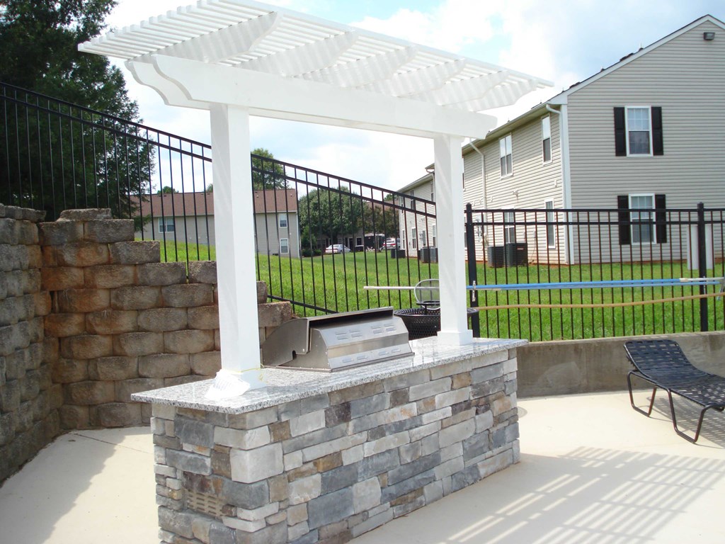 a stone fireplace and a white pergola on a patio