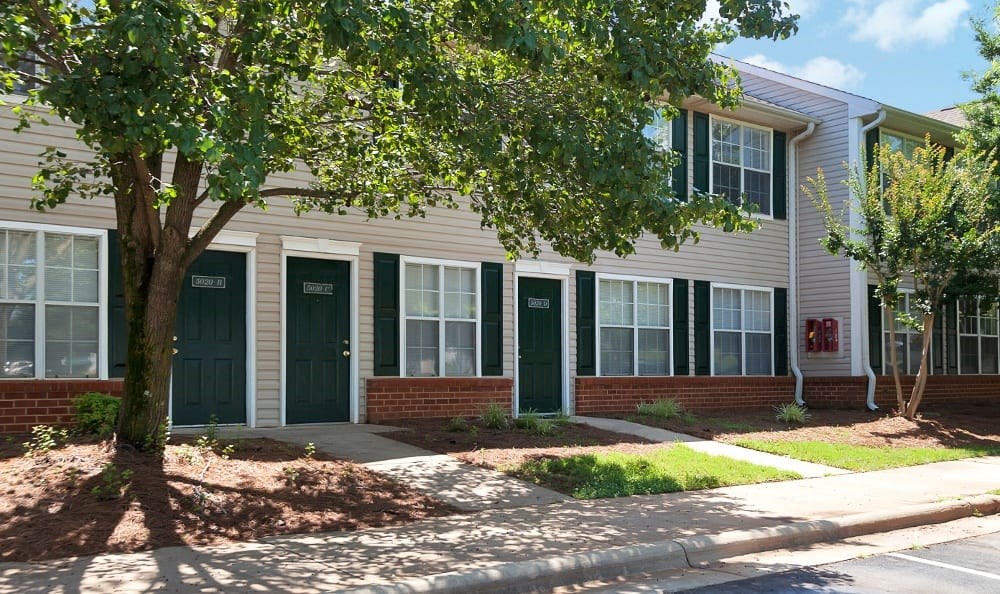 a house with green doors and a tree in front of it