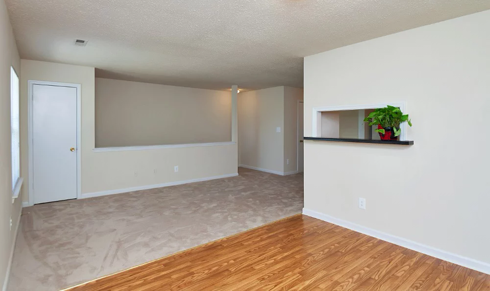 an empty living room with wood flooring and a white wall