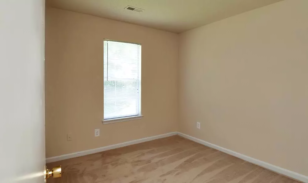 an empty room with a window and wooden floors