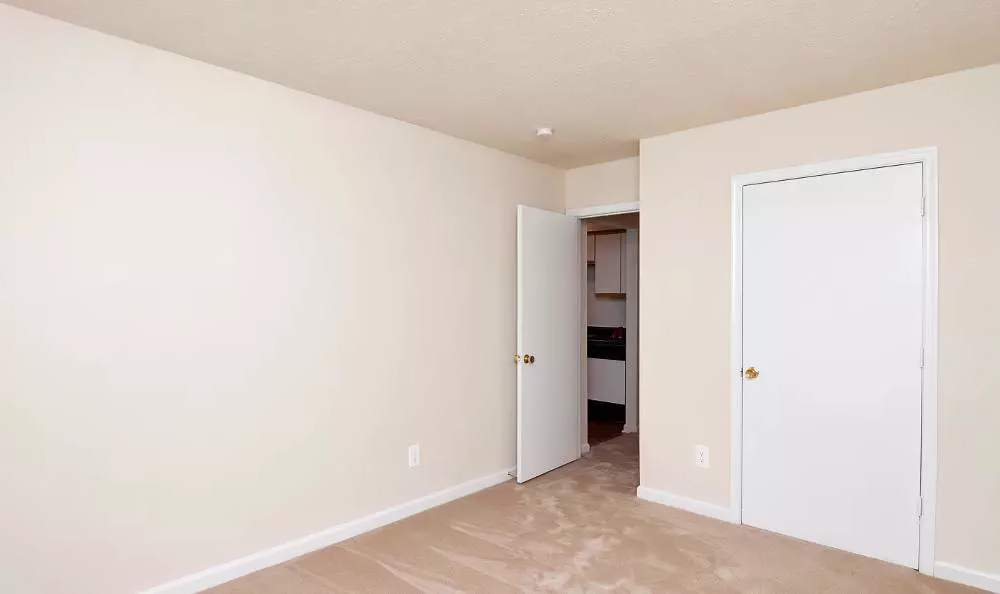 an empty room with a door to a bathroom and a closet
