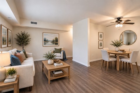 A living room with a white couch, a wooden coffee table, and a dining table with chairs.